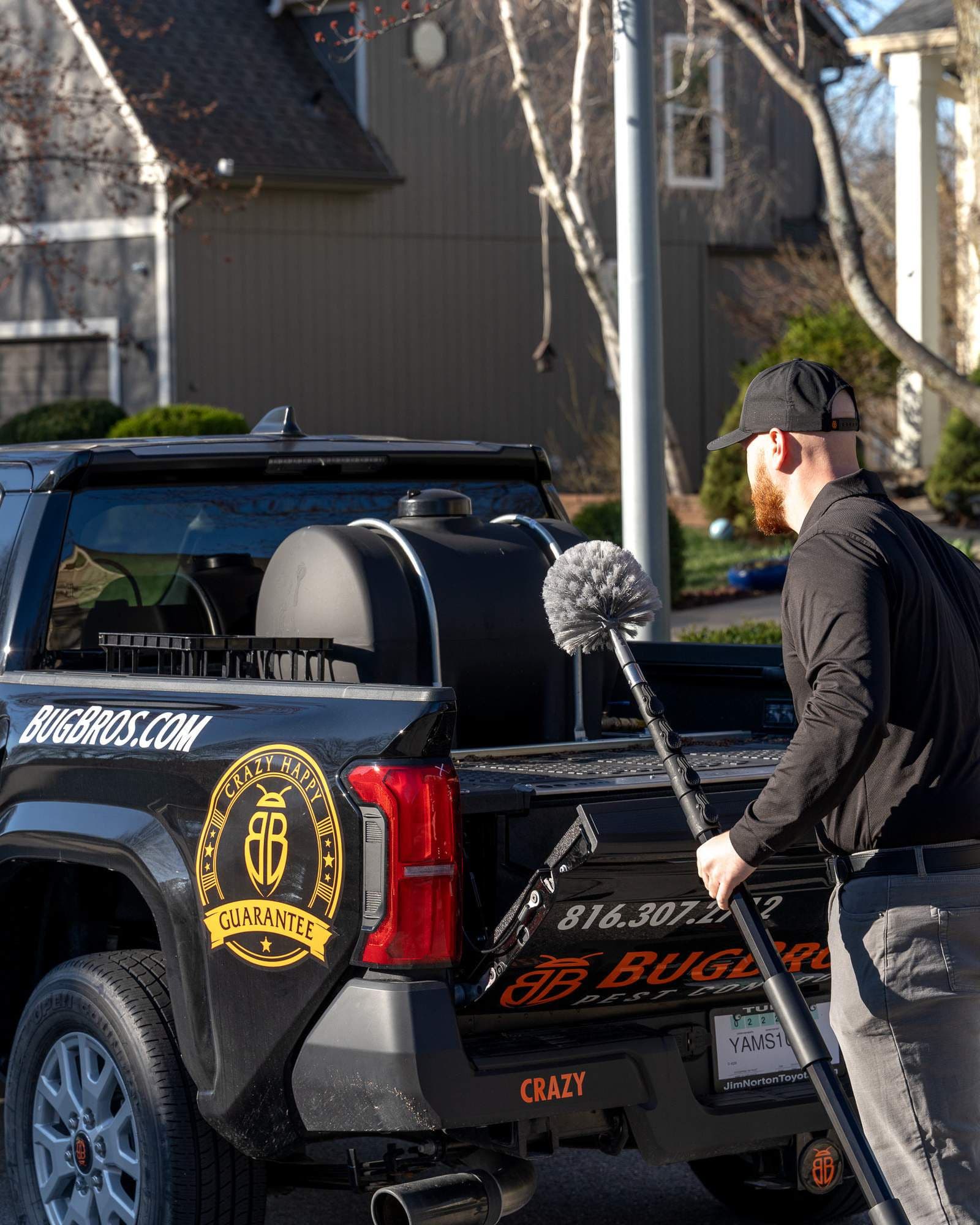 BugBros Pest Control technician preparing equipment at branded truck in Kansas City neighborhood
