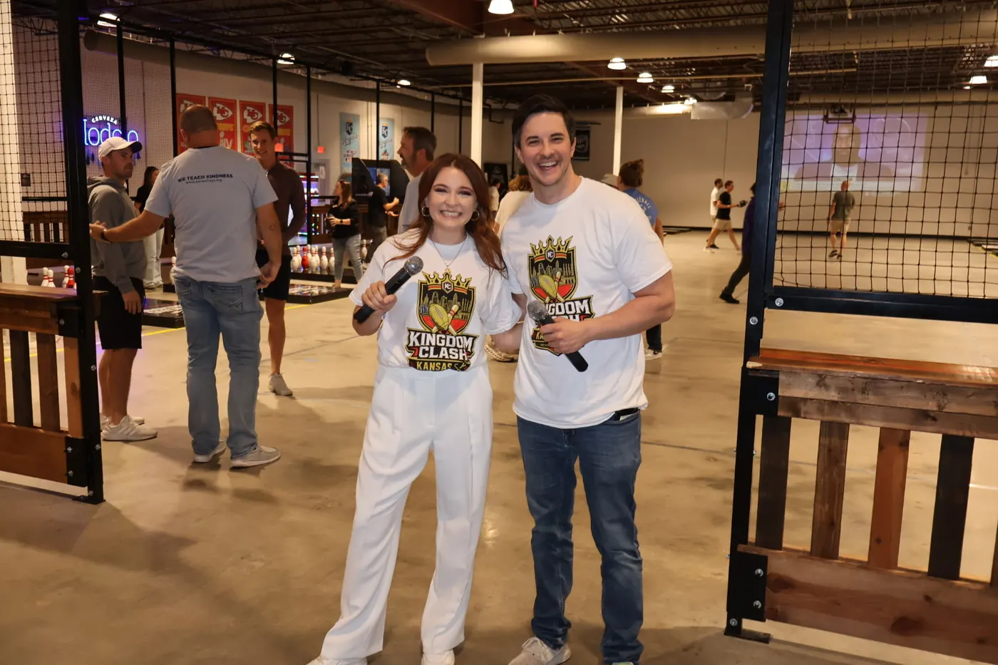 The two event emcees holding microphones beside the lanes